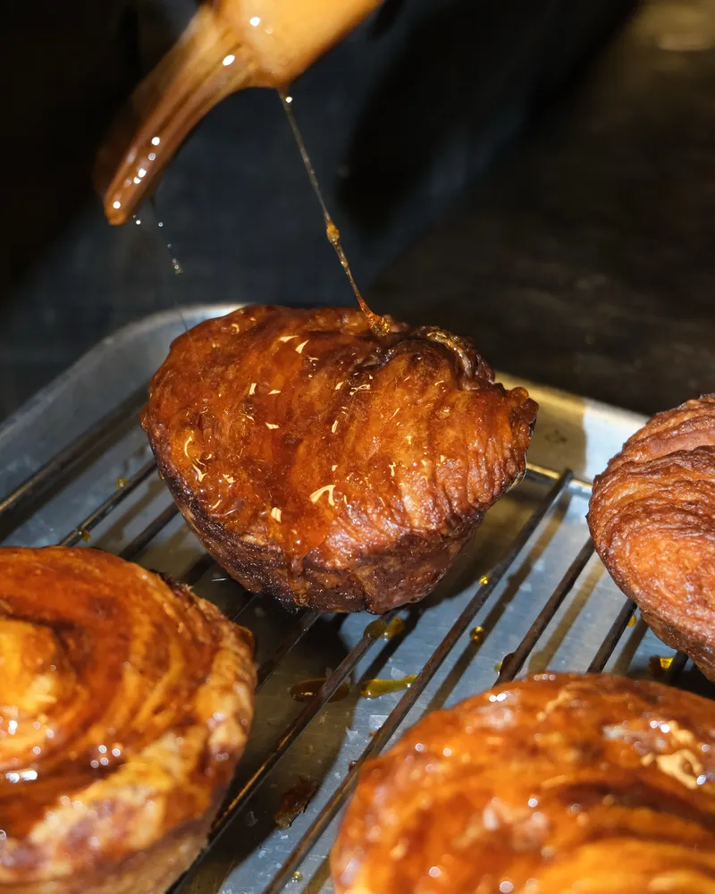 Honey being drizzled over a kouign-amann
