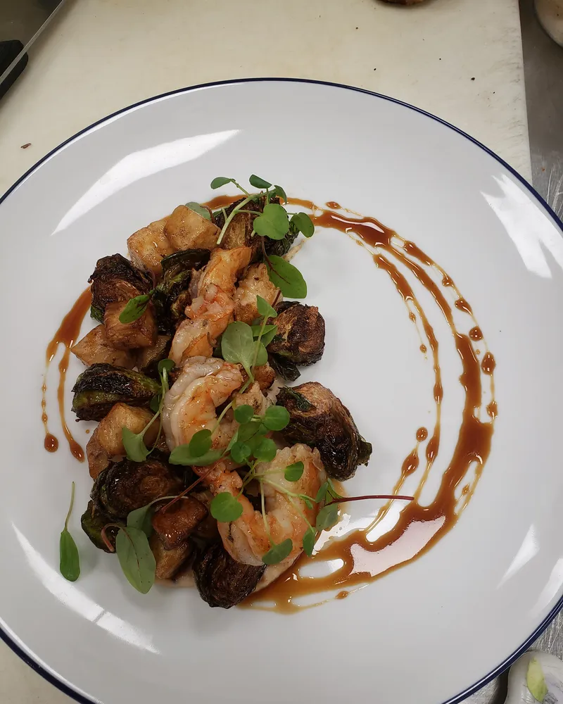 Plated shrimp with charred Brussels sprouts and a sauce swirl